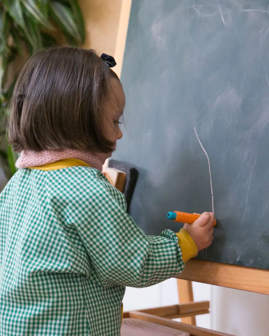 Niña pintando con tiza en la pizarra